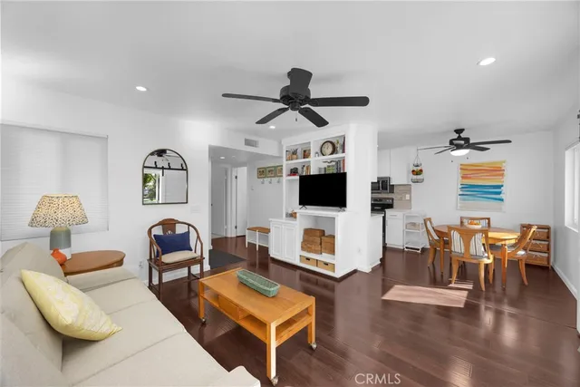 a living room with furniture kitchen view and a flat screen tv