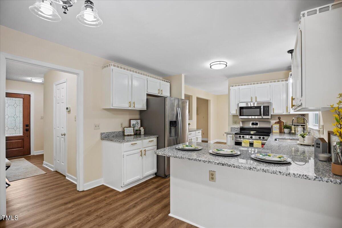 4309 Birmingham Way Raleigh, NC 27604 - Photo 12 of 60 a kitchen with stainless steel appliances granite countertop a stove top oven a refrigerator a sink and dishwasher with wooden floor