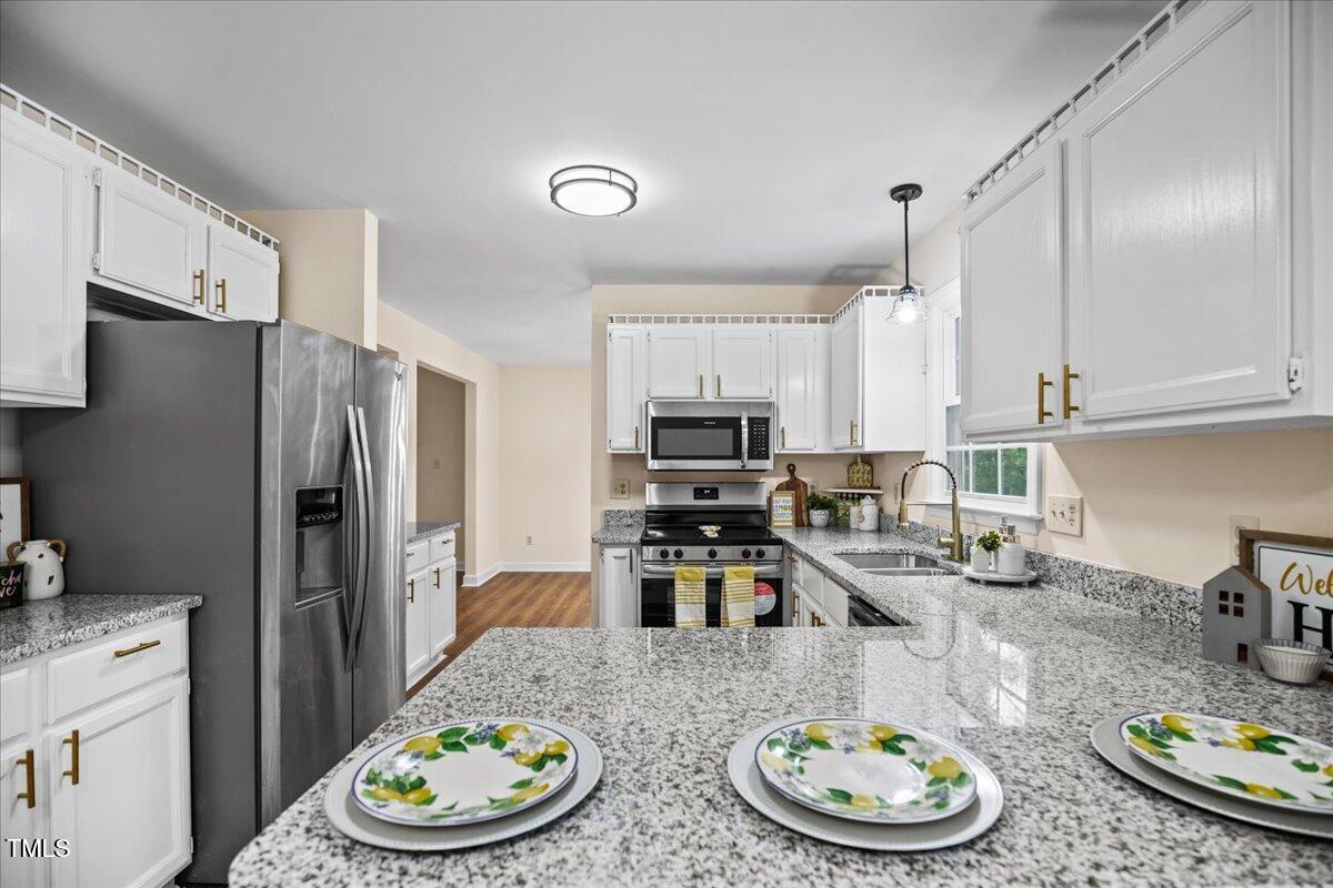 4309 Birmingham Way Raleigh, NC 27604 - Photo 14 of 60 a kitchen with stainless steel appliances kitchen island granite countertop a sink a refrigerator and wooden floor