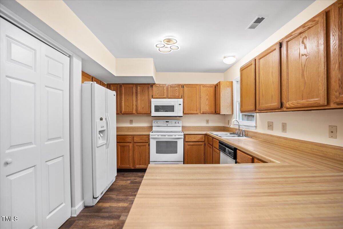 4309 Birmingham Way Raleigh, NC 27604 - Photo 50 of 60 a kitchen with stainless steel appliances granite countertop a refrigerator a sink dishwasher and wooden cabinets with wooden floor
