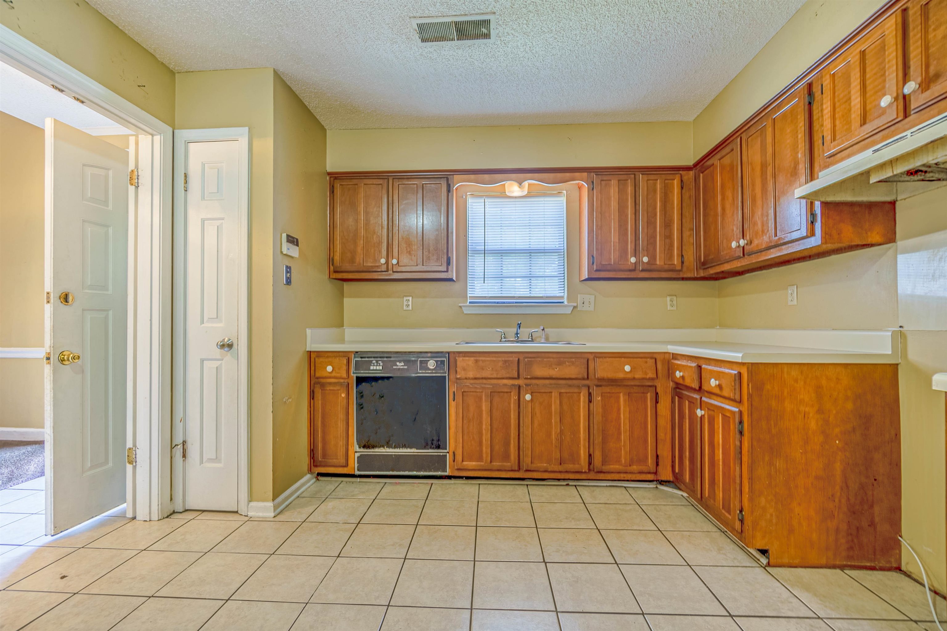 5891 Ridgehill Drive Memphis, TN 38141 - Photo 7 of 13 Kitchen with black dishwasher, a textured ceiling, light tile patterned floors, and sink