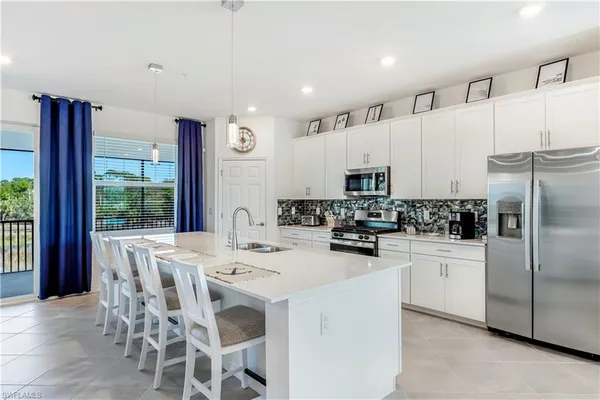 a kitchen with stainless steel appliances kitchen island granite countertop a table chairs and a refrigerator