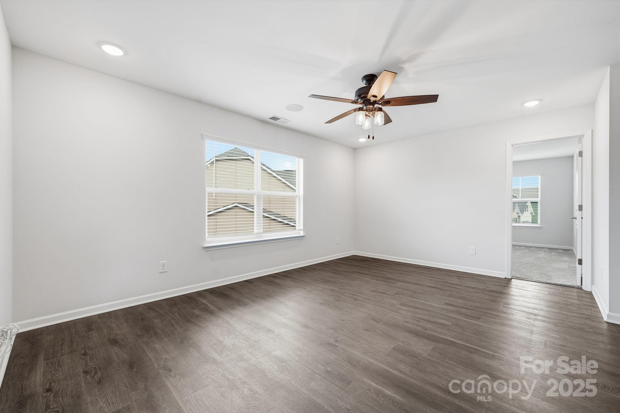 2612 Keady Mill Loop Kannapolis, NC 28081 - Photo 25 of 48 an empty room with wooden floor ceiling fan and windows