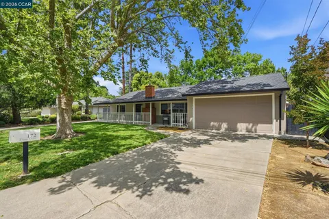 a front view of a house with a garden and trees