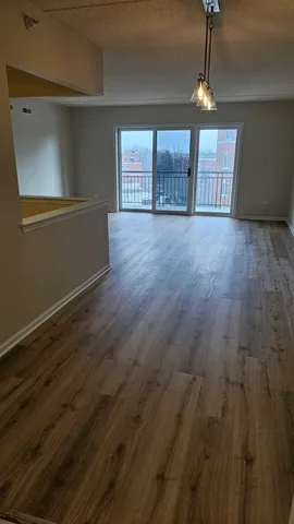 an empty room with wooden floor chandelier and windows