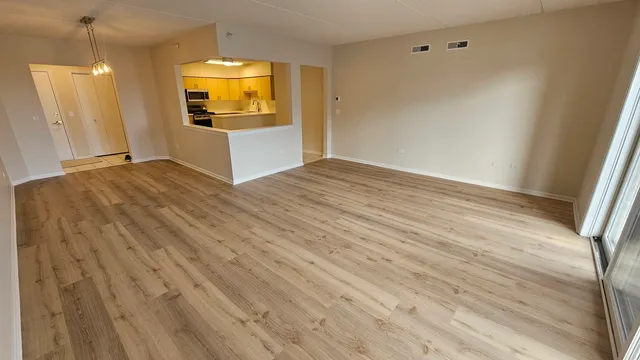 a view of a room with wooden floor and kitchen view