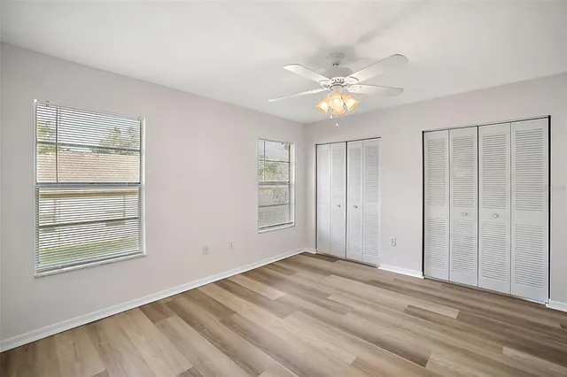 a view of empty room with wooden floor and fan