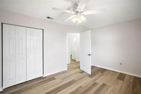 an empty room with wooden floor and ceiling fan