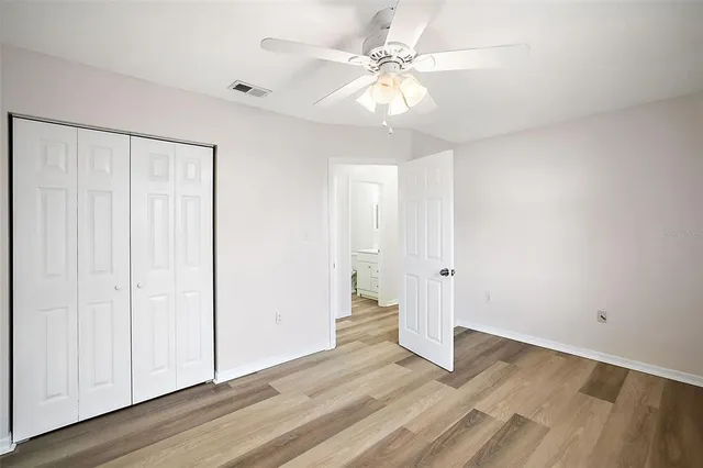 an empty room with wooden floor and ceiling fan