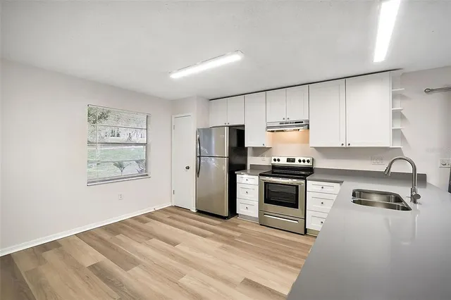 a kitchen with granite countertop a refrigerator stove and sink