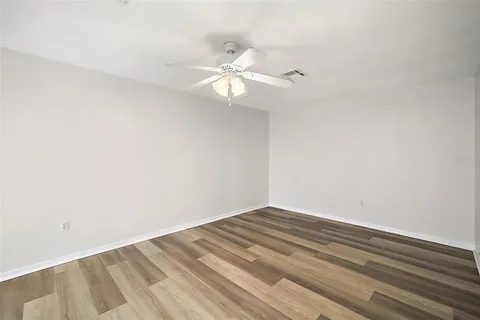 a view of a room with a ceiling fan and wooden floor