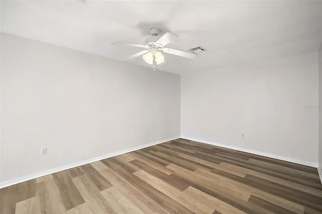 a view of a room with a ceiling fan and wooden floor