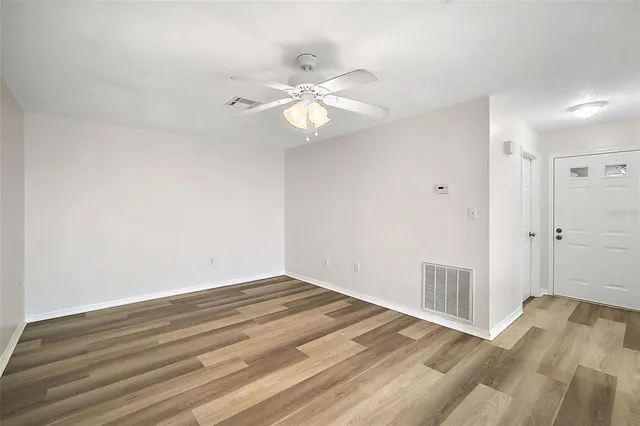 a view of a room with wooden floor and a ceiling fan