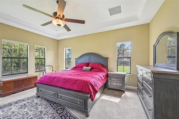 a bedroom with a bed a chandelier and dresser
