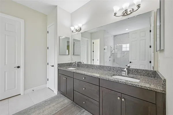 a bathroom with a granite countertop double vanity sink and mirror