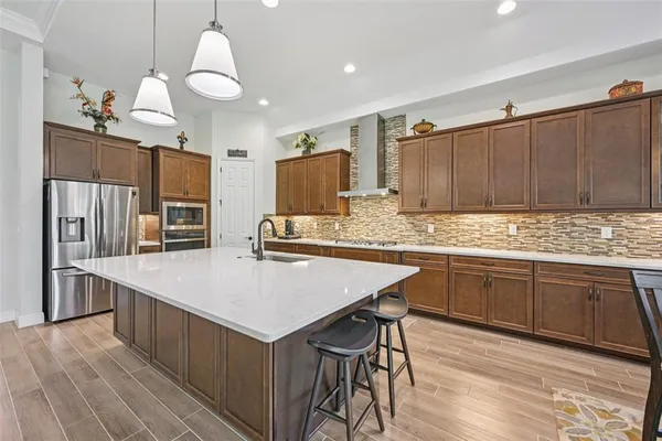 a kitchen with kitchen island granite countertop wooden cabinets a stove a sink and dishwasher a refrigerator with wooden floor