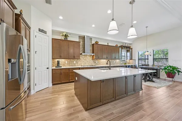 a large kitchen with a center island wooden floor stainless steel appliances and windows