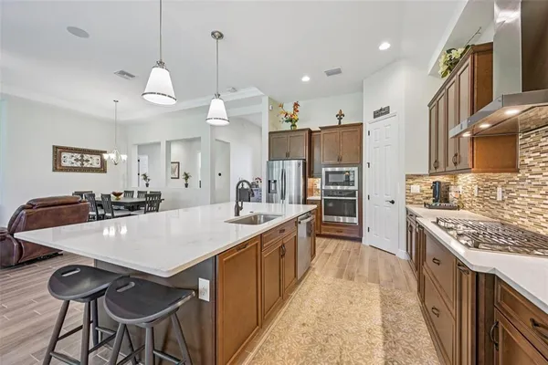 a large kitchen with stainless steel appliances granite countertop a stove a sink a oven a dining table and chairs