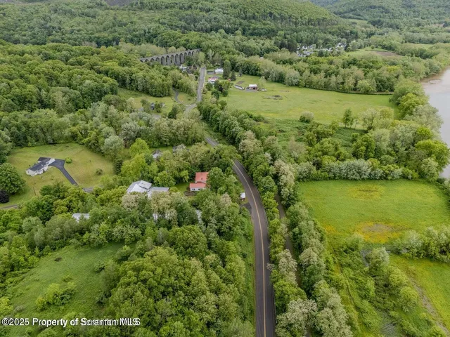 an aerial view of residential houses with outdoor space and trees all around