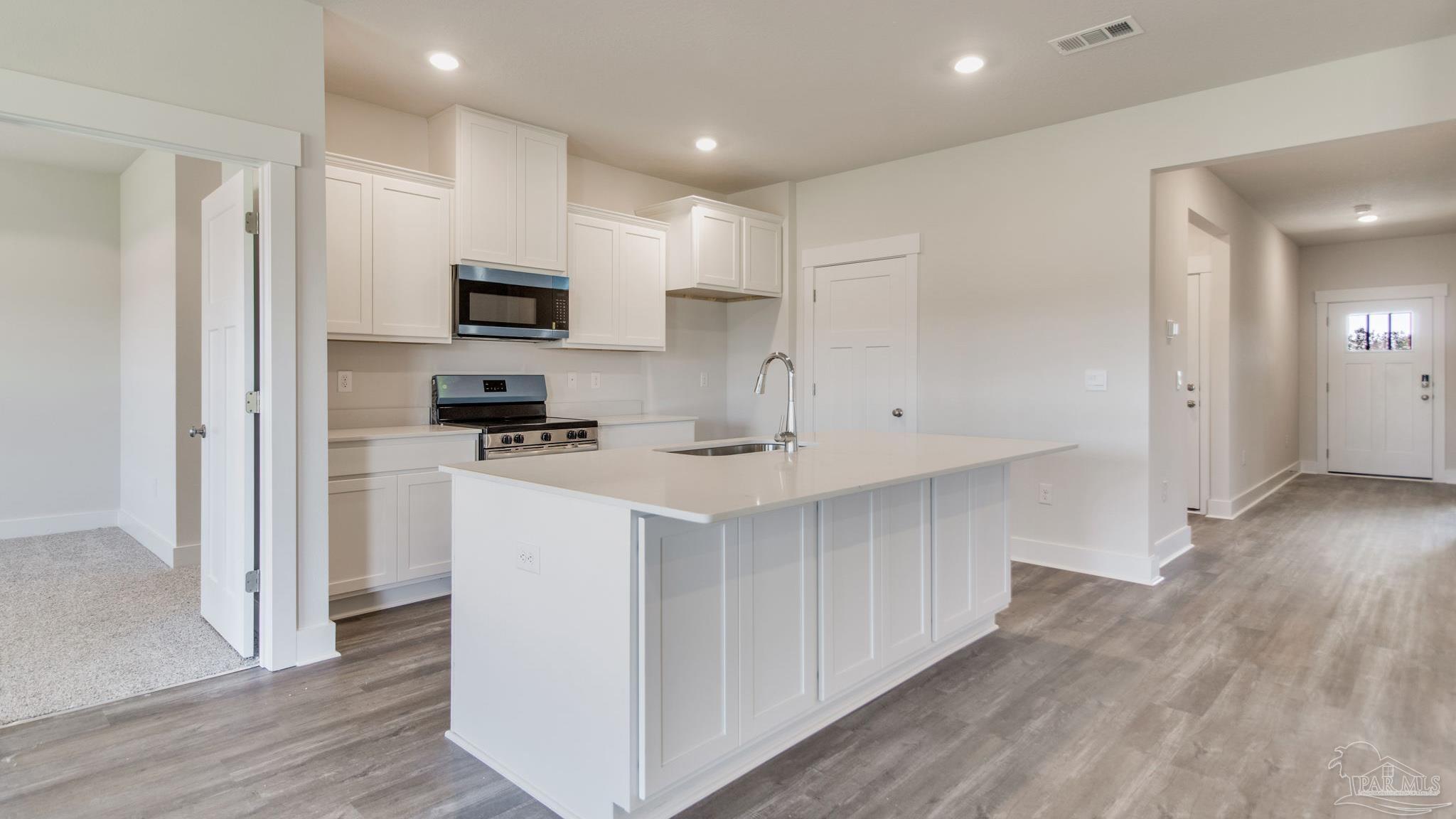 3034 Serviceberry Road Cantonment, FL 32533 - Photo 5 of 33 a kitchen with white cabinets and stainless steel appliances