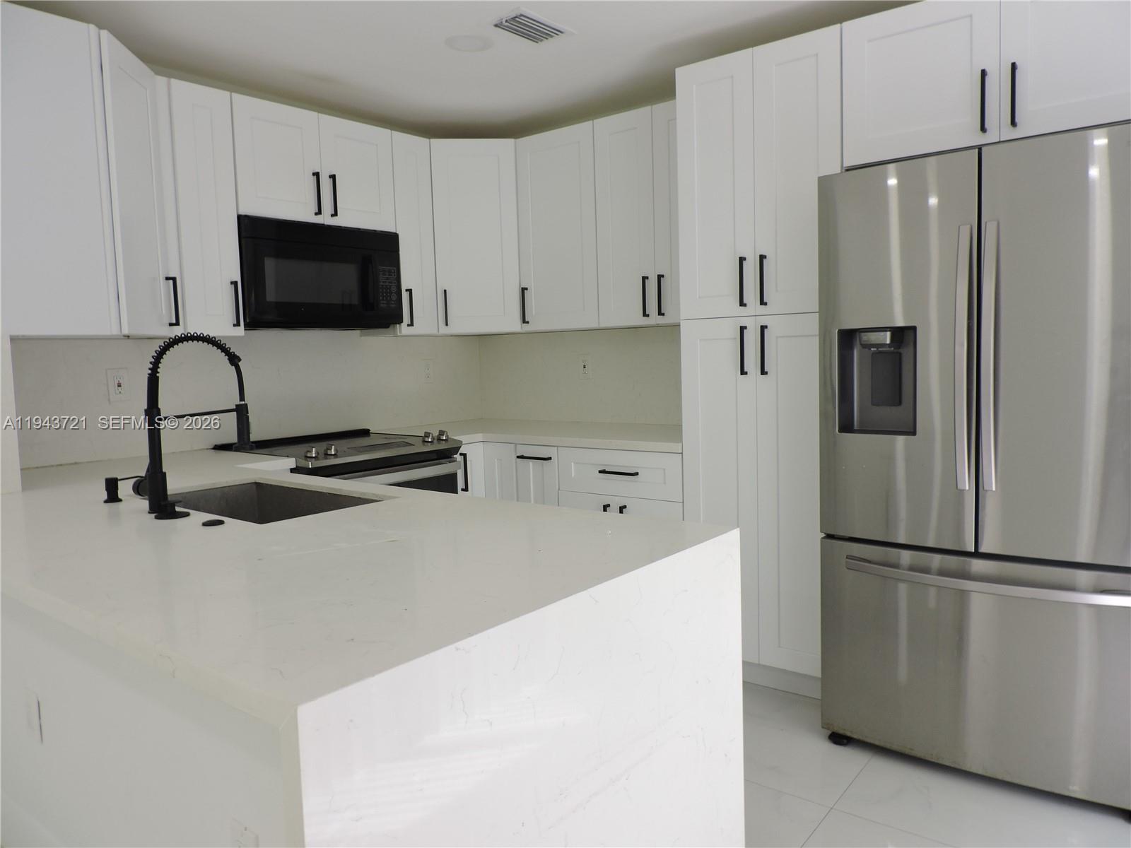 17975 Southwest 140th Court, Unit 17975 Miami, FL 33177 - Photo 19 of 27 a kitchen with stainless steel appliances a refrigerator sink and white cabinets