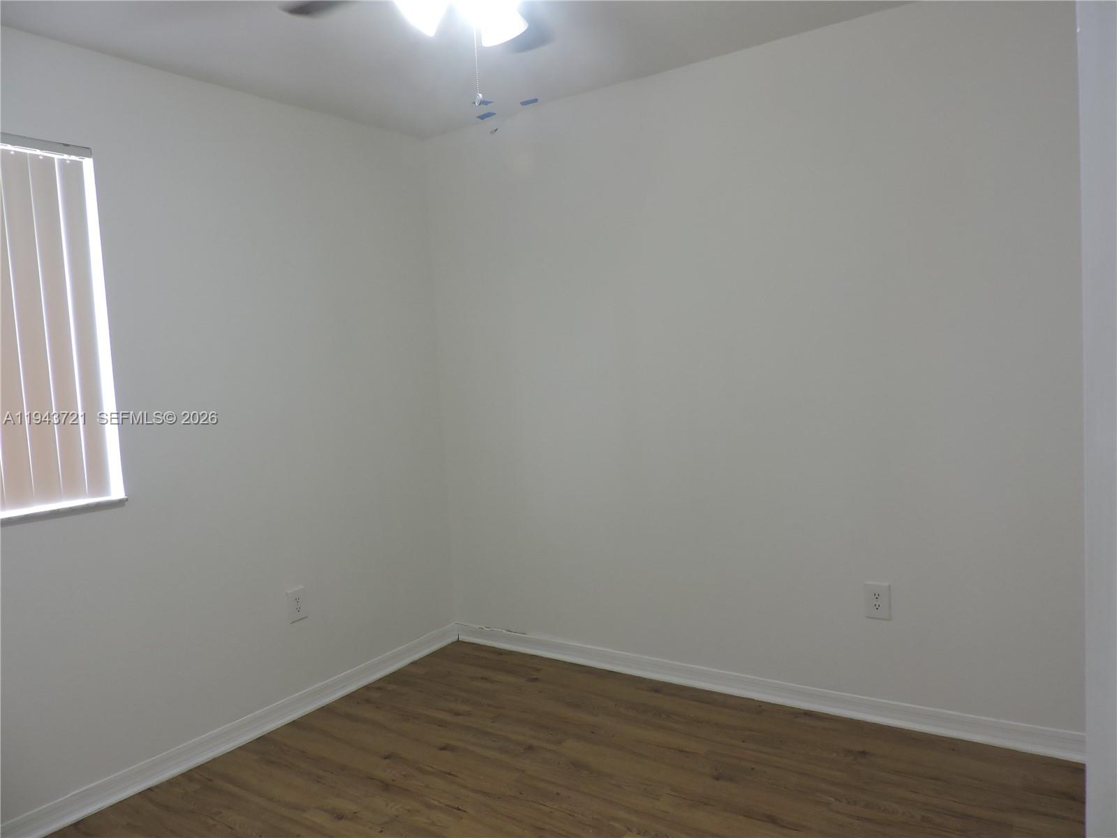 17975 Southwest 140th Court, Unit 17975 Miami, FL 33177 - Photo 26 of 27 a view of an empty room with wooden floor and a window