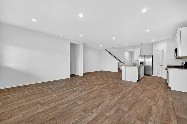 a view of kitchen and empty room with wooden floor