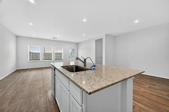 a kitchen with granite countertop a sink and dishwasher with wooden floor