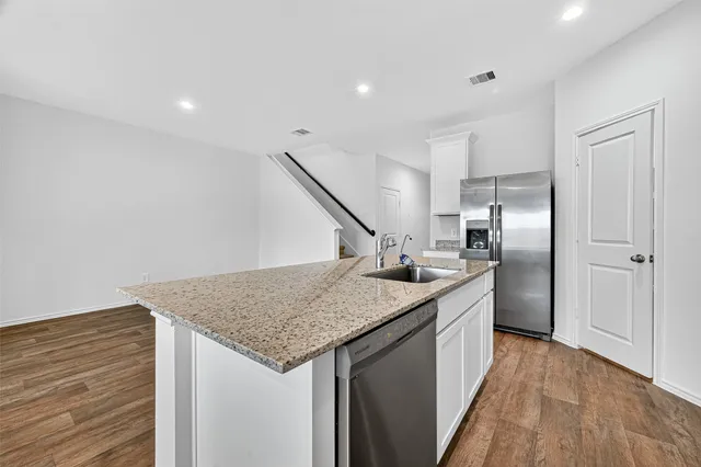 a kitchen with stainless steel appliances granite countertop a sink and a refrigerator