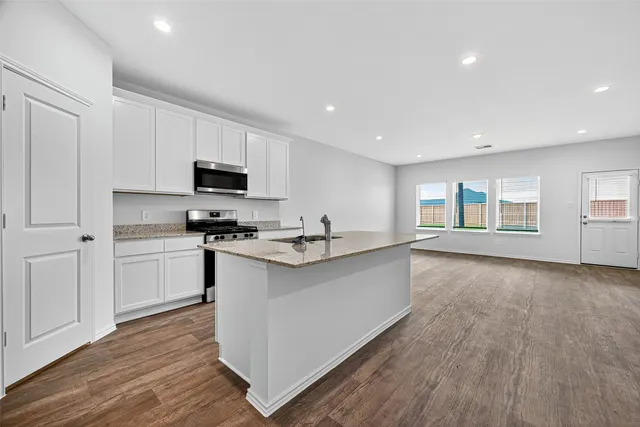 a kitchen with granite countertop a stove top oven a sink dishwasher and a refrigerator with wooden floor