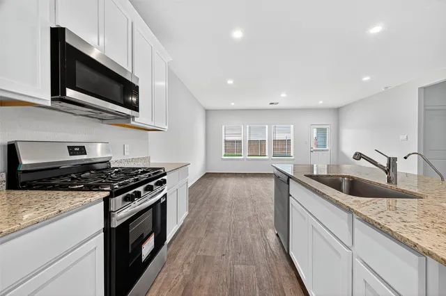 a kitchen with stainless steel appliances granite countertop a sink a stove and a wooden floors
