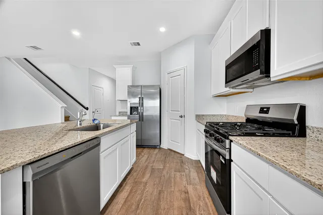 a kitchen with stainless steel appliances granite countertop a stove a sink and a refrigerator