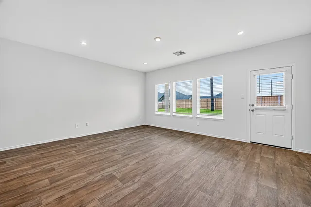 a view of an empty room with a window and wooden floor
