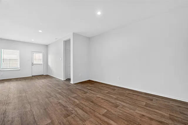 a view of an empty room with wooden floor and window