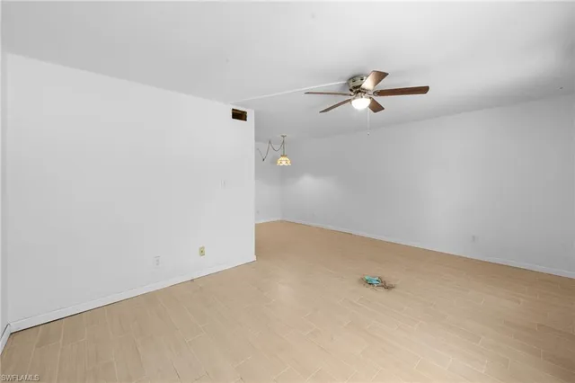 an empty room with a window and a ceiling fan