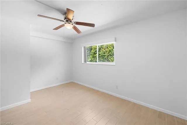 an empty room with a window and a fan