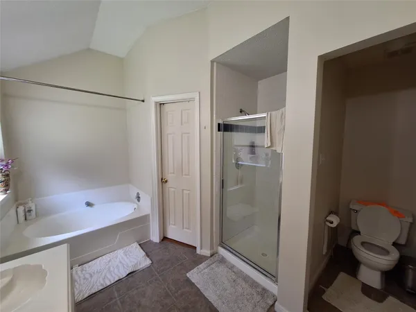 a bedroom with a bed window and walk in closet with wooden floor
