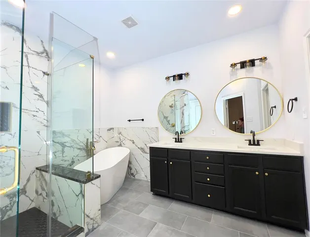 a spacious bathroom with a double vanity sink a mirror a bathtub and next to a window