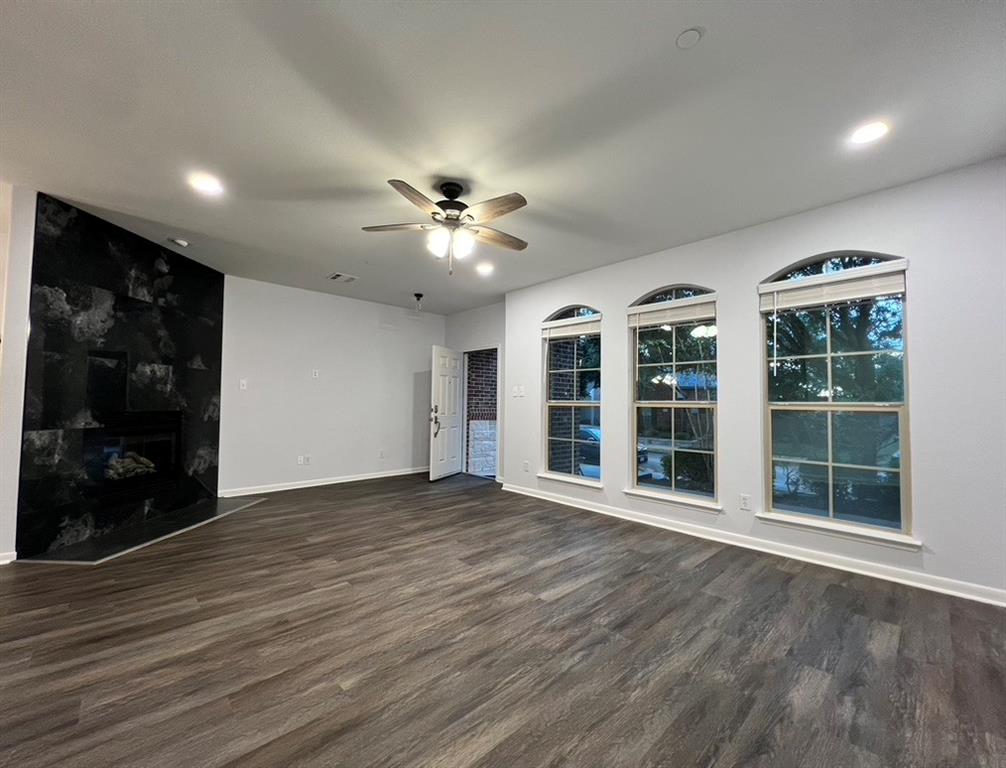 1902 Downing Street Allen, TX 75013 - Photo 3 of 19 Unfurnished living room with dark wood-type flooring, ceiling fan, and a premium fireplace