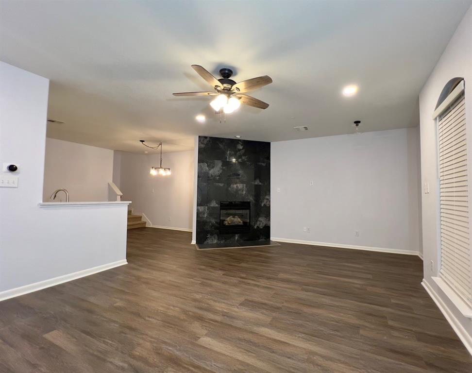 1902 Downing Street Allen, TX 75013 - Photo 4 of 19 Unfurnished living room featuring dark wood finished floors, a ceiling fan, a fireplace, and stairs