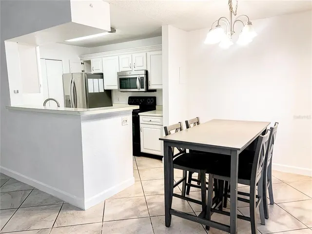 a kitchen with stainless steel appliances kitchen island granite countertop a table chairs microwave and sink