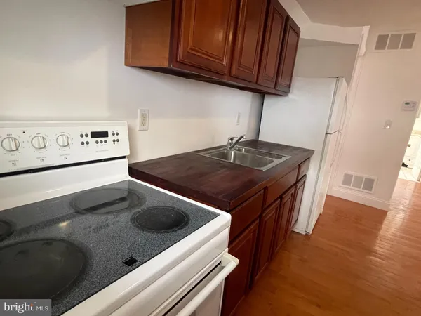 a kitchen with stainless steel appliances granite countertop a stove a refrigerator and a sink with wooden cabinets