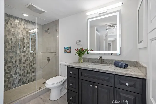 a spacious bathroom with a granite countertop sink a mirror and a shower