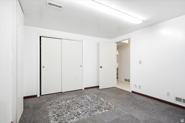 7050 South 260 East Midvale, UT 84047 - Photo 23 of 28 Carpeted room with white walls, featuring sliding closet doors and a wall-mounted fluorescent light fixture