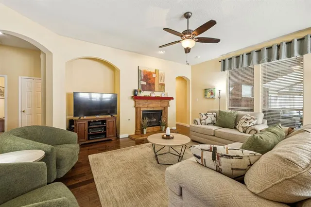 a living room with furniture a ceiling fan a fireplace and a large window