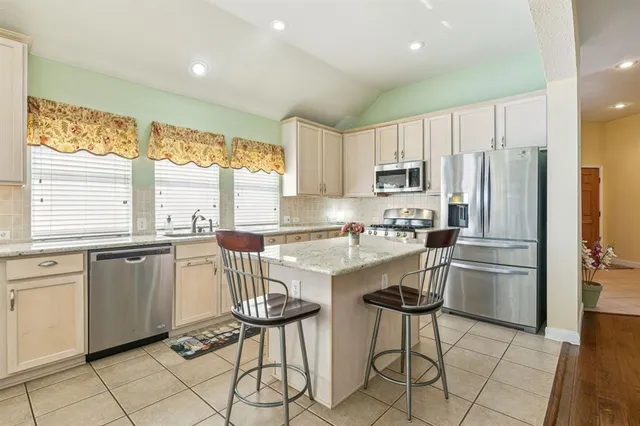 a kitchen with stainless steel appliances granite countertop a stove a sink a refrigerator and a refrigerator