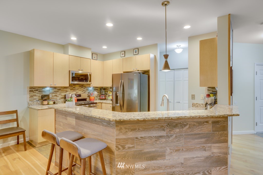 102 South 49th Street, Unit A Renton, WA 98055 - Photo 17 of 35 a kitchen with stainless steel appliances kitchen island granite countertop a refrigerator a stove a sink dishwasher with a dining table and chairs
