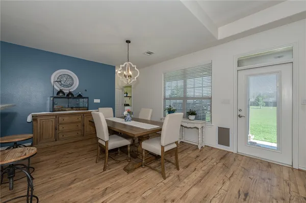 a dining room with wooden floor a chandelier a wooden table and chairs