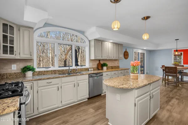 a kitchen with stainless steel appliances granite countertop a refrigerator a stove top oven a sink dishwasher and white cabinets with wooden floor