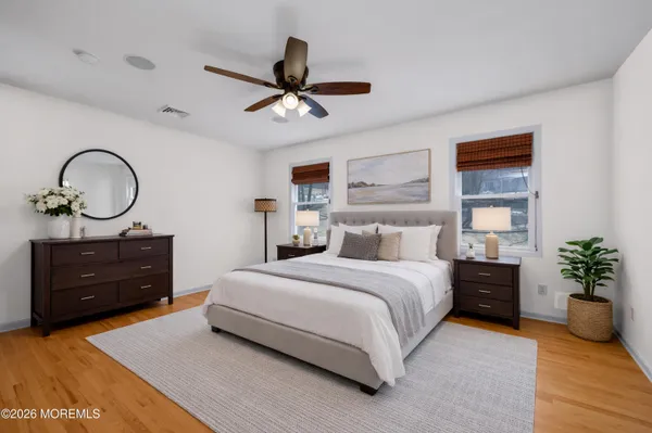 a view of an empty room with wooden floor and a ceiling fan